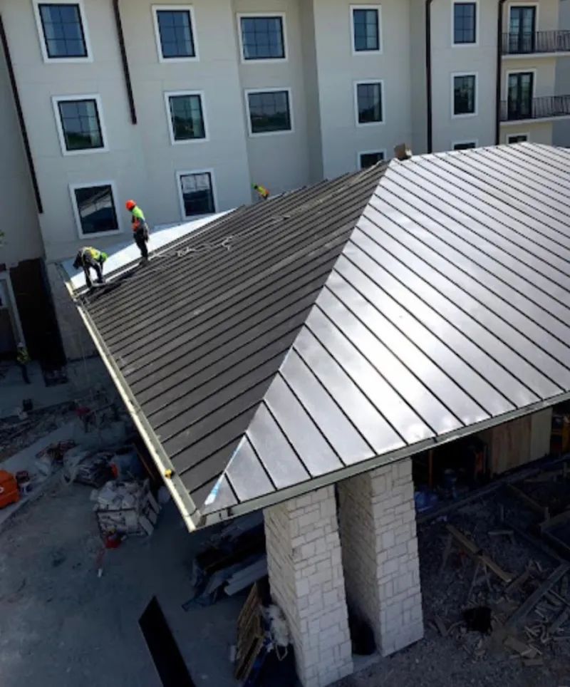 Crew installing standing seam metal roof panels on a commercial project in Kernersville